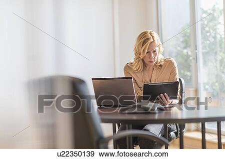 Business woman using laptop and tablet pc in office View Large Photo Image Stock Photo - Business woman using laptop and tablet pc in office. Fotosearch