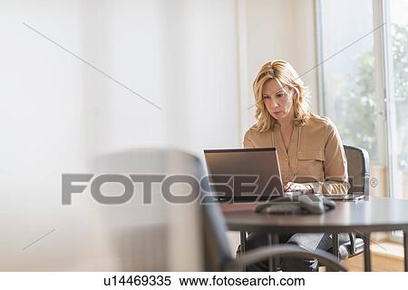 Stock Photography - Business woman using laptop in office. Fotosearch