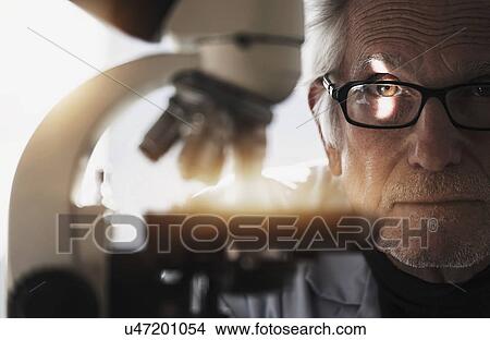 Close up of man behind microscope View Large Photo Image Picture - Close up of man behind microscope. Fotosearch