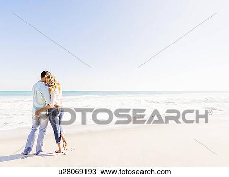 Stock Image - Couple embracing on beach. Fotosearch