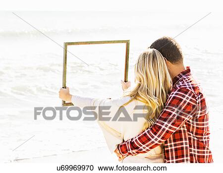 Stock Image - Couple holding frame. Fotosearch