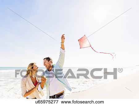 Stock Photo - Couple on beach with kite. Fotosearch