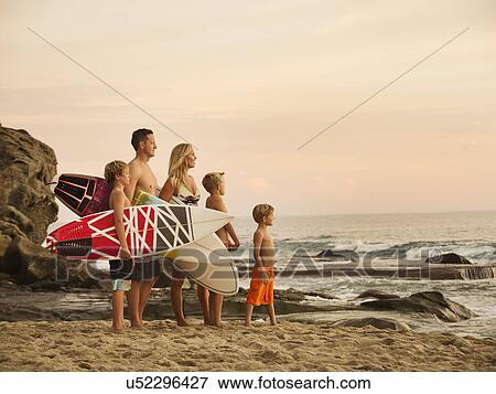 Stock Photo - Family with three children (6-7, 10-11, 14-15) looking at sea. Fotosearch