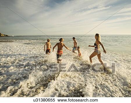 Stock Photography - Family with three children (6-7, 10-11, 14-15) running on beach. Fotosearch