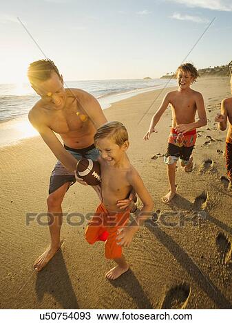 Father playing football on beach with his three sons (6-7, 10-11, 14-15) View Large Photo Image Stock Image - Father playing football on beach with his three sons (6-7, 10-11, 14-15). Fotosearch