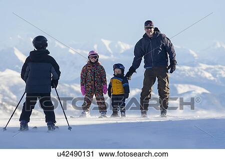 Stock Image - Father skiing with children (6-7, 8-9). Fotosearch