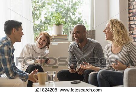 Friends hanging out in living room View Large Photo Image Stock Photo - Friends hanging out in living room. Fotosearch