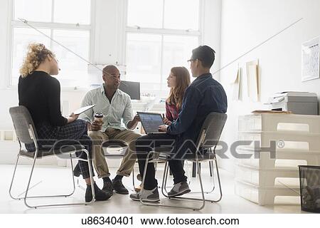Stock Image - Friends having business meeting in office. Fotosearch