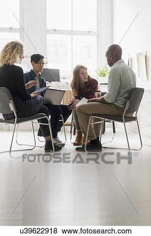 Stock Photo - Friends having business meeting in office. Fotosearch