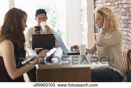 Friends sitting in cafe, using laptops and digital tablet View Large Photo Image Stock Image - Friends sitting in cafe, using laptops and digital tablet. Fotosearch