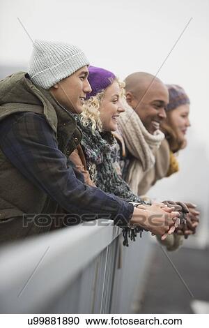 Stock Image - Friends standing on bridge and laughing. Fotosearch
