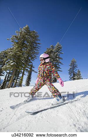 Stock Image - Girl (8-9) skiing in mountains. Fotosearch
