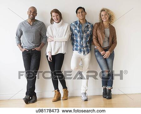 Group of friends standing in front of white wall View Large Photo Image Stock Image - Group of friends standing in front of white wall. Fotosearch