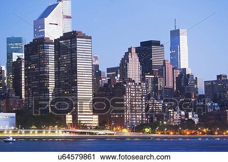 Stock Image - Illuminated cityscape at dusk. Fotosearch