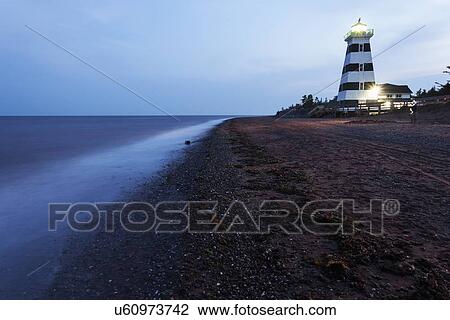 Stock Image - Illuminated West Point Lighthouse seen from empty beach. Fotosearch