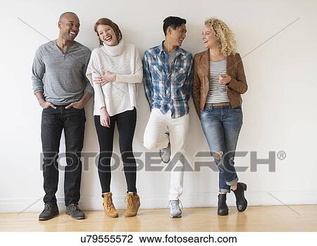 Laughing friends standing against white wall View Large Photo Image Stock Image - Laughing friends standing against white wall. Fotosearch