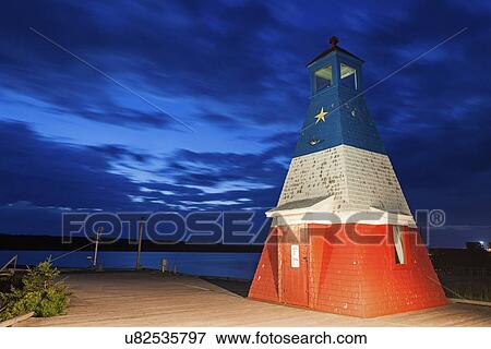 Stock Photo - Lighthouse in harbor at dusk. Fotosearch