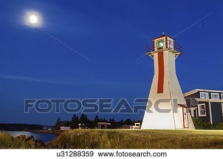 Stock Photo - Lighthouse on grassy hill under full moon. Fotosearch