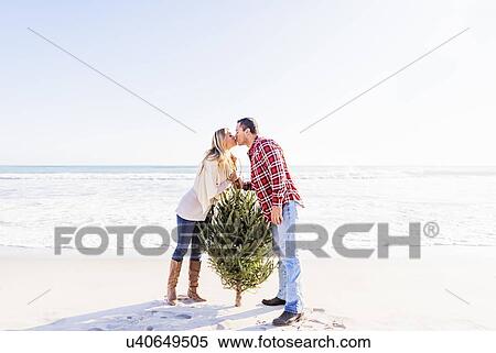 Loving couple kissing on beach beside tree View Large Photo Image Stock Photography - Loving couple kissing on beach beside tree. Fotosearch