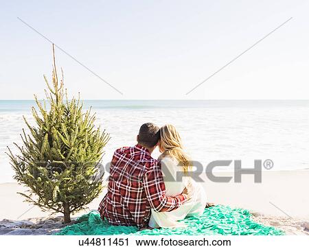 Loving couple sitting on beach with tree View Large Photo Image Stock Image - Loving couple sitting on beach with tree. Fotosearch