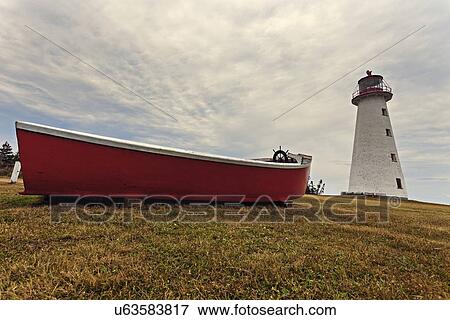 Stock Photo - Low angle view of Point Prim Lighthouse and red boat. Fotosearch
