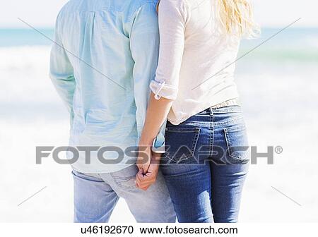Stock Image - Man and woman holding hands on beach. Fotosearch