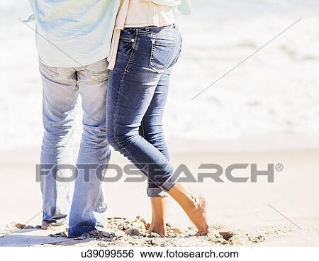 Stock Photograph - Man and woman standing together on beach. Fotosearch