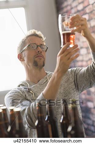 Man examining glass of beer View Large Photo Image Stock Image - Man examining glass of beer. Fotosearch
