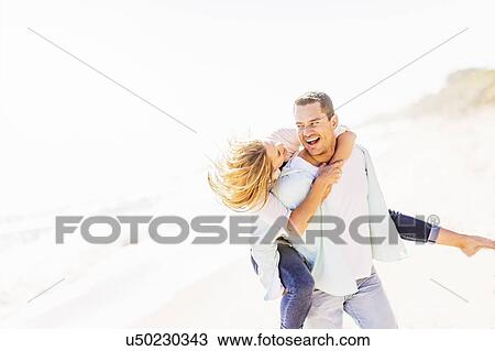 Stock Image - Man giving woman piggyback ride. Fotosearch