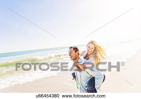 Stock Image - Man giving woman piggyback ride. Fotosearch