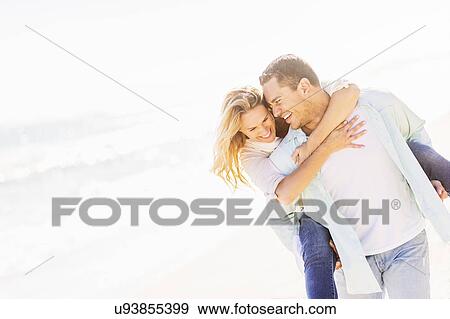 Stock Photo - Man giving woman piggyback ride. Fotosearch