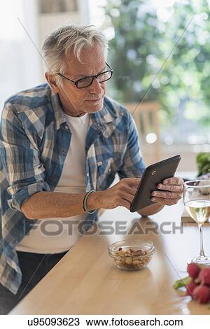 Man in kitchen using tablet View Large Photo Image Stock Image - Man in kitchen using tablet. Fotosearch