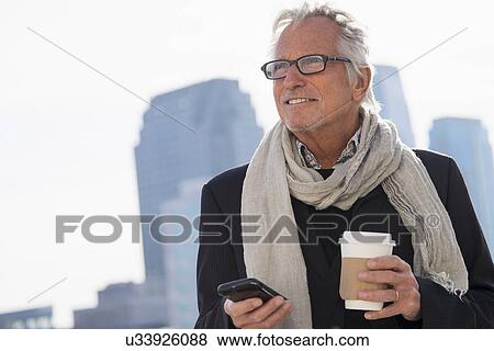 Stock Photo - Man in street with coffee and smartphone. Fotosearch