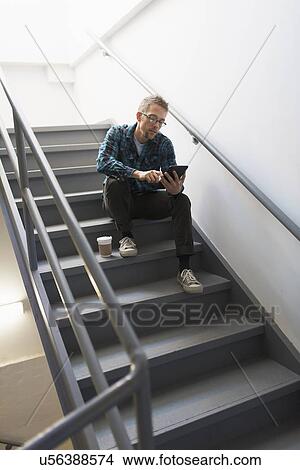 Picture - Man sitting on steps using tablet pc. Fotosearch