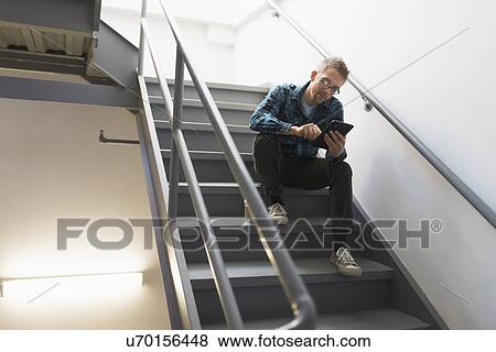 Man sitting on steps using tablet pc View Large Photo Image Stock Photo - Man sitting on steps using tablet pc. Fotosearch