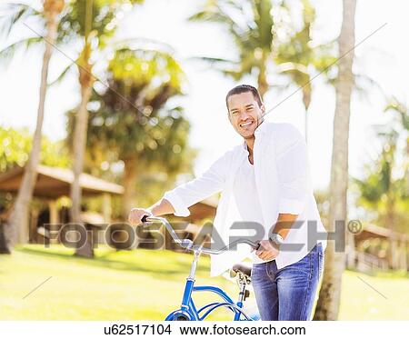 Man with bicycle with palm trees in background View Large Photo Image Picture - Man with bicycle with palm trees in background. Fotosearch