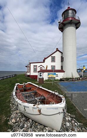 Stock Photo - Matane Lighthouse and empty white rowboat on gravel pile. Fotosearch