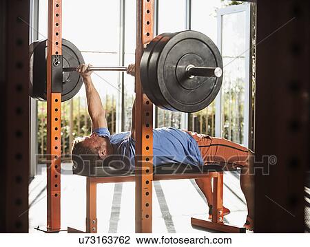 Stock Image - Mature man bench pressing. Fotosearch