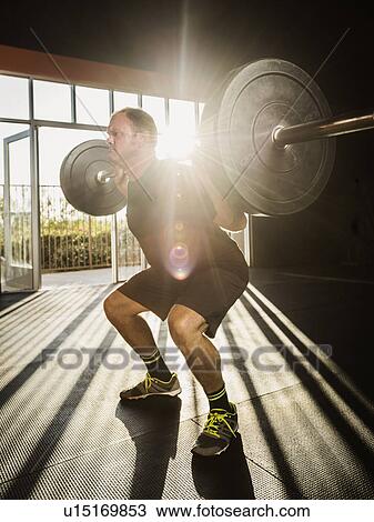Stock Image - Mature man doing squats. Fotosearch