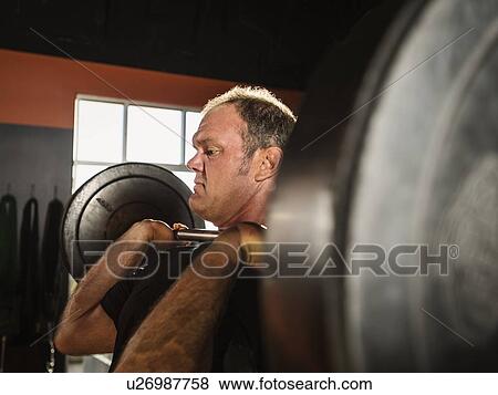 Stock Photo - Mature man shoulder pressing. Fotosearch