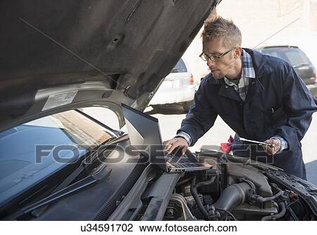 Mechanic using laptop while repairing car View Large Photo Image Stock Image - Mechanic using laptop while repairing car. Fotosearch