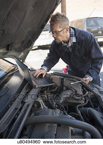 Mechanic using laptop while repairing car View Large Photo Image Stock Image - Mechanic using laptop while repairing car. Fotosearch