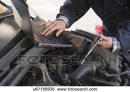 Mechanic using laptop while repairing car View Large Photo Image Stock Photography - Mechanic using laptop while repairing car. Fotosearch