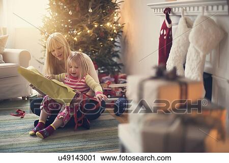 Stock Image - Mother and daughter (4-5) opening christmas presents. Fotosearch