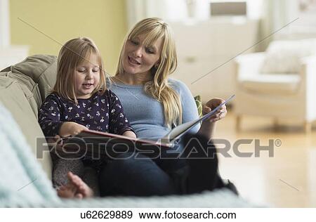 Mother and daughter (4-5) sitting on couch and reading book View Large Photo Image Stock Photo - Mother and daughter (4-5) sitting on couch and reading book. Fotosearch