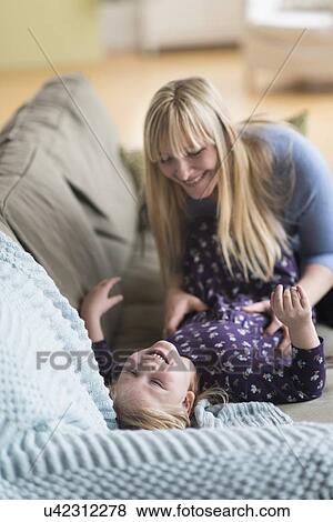 Stock Photo - Mother tickling her daughter (4-5). Fotosearch