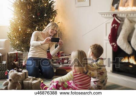 Mother with children (4-5, 6-7) opening christmas presents and taking photos View Large Photo Image Stock Photo - Mother with children (4-5, 6-7) opening christmas presents and taking photos. Fotosearch