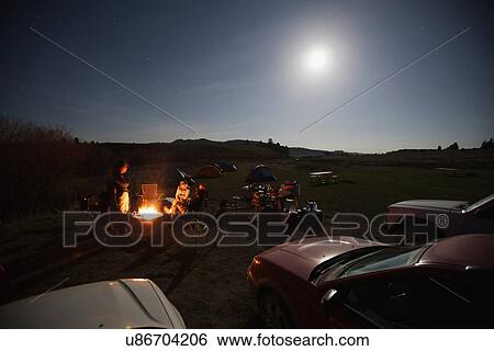 Stock Photograph - People sitting next to campfire. Fotosearch