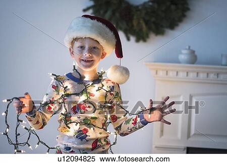 Stock Photography - Portrait of boy (6-7) holding christmas lights. Fotosearch