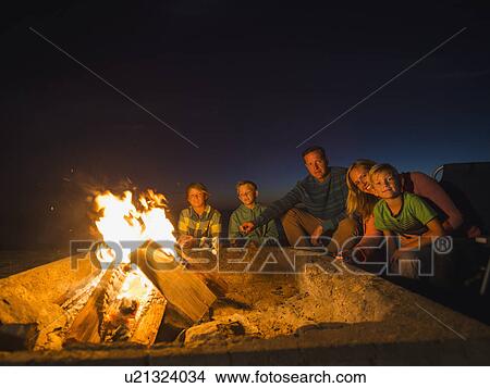 Picture - Portrait of family with three children (6-7, 10-11, 14-15) cooking marshmallows . Fotosearch
